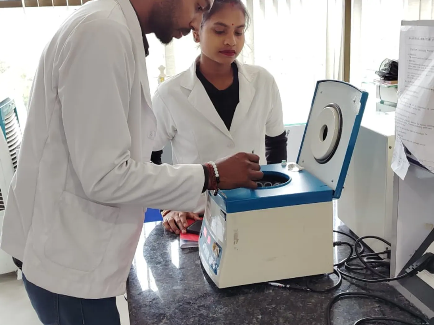 Two trainees operating laboratory equipment under supervision